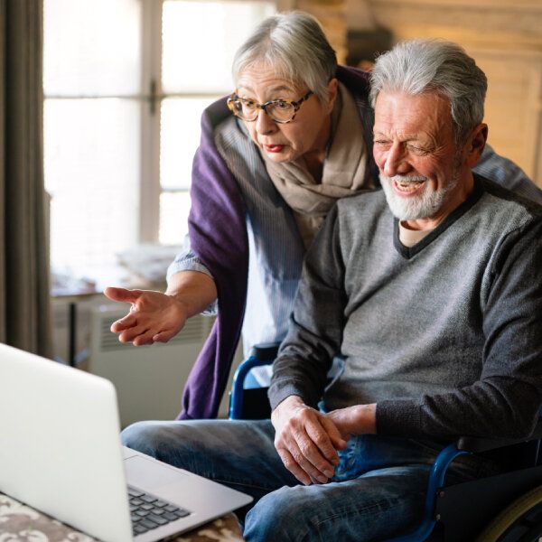 Un couple de seniors discutent devant un ordinateur portable.