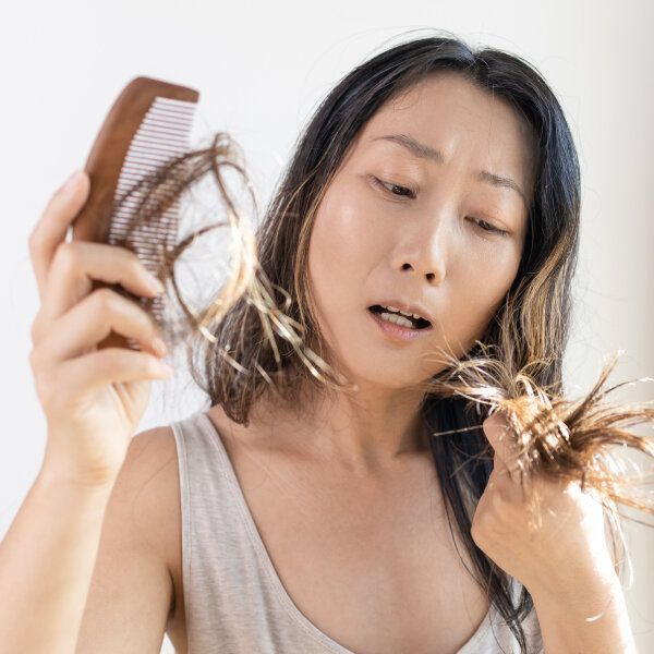 Une femme observe ses cheveux accrochés au peigne.
