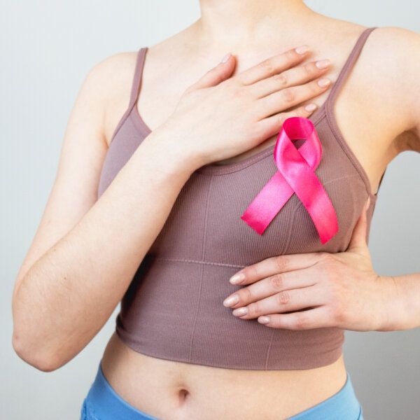 Buste de femme se posant les mains autour du sein, symbole de lutte contre le cancer du sein rose sur le sein gauche.