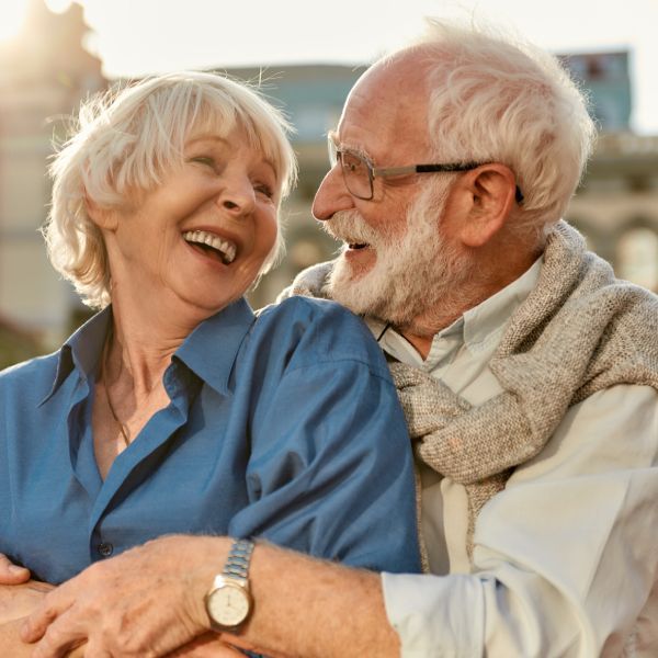 Un couple de seniors se regardent en riant.