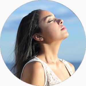 Une jeune femme aux yeux fermés lève le menton et respire.