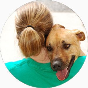 Une femme porte un chien sur son épaule.