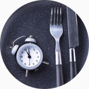 Une petite horloge à coté d'une fourchette et un couteau.