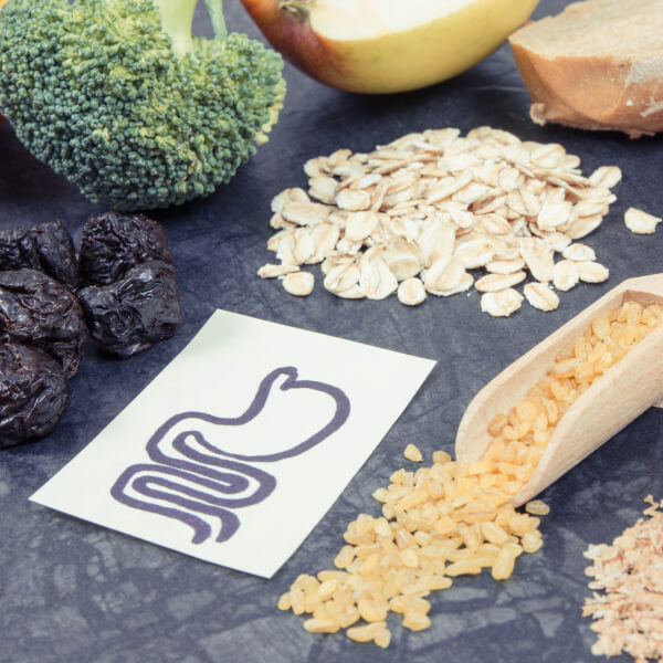 Des aliments sains, féculents, légumes, autour d'un dessin de système digestif.