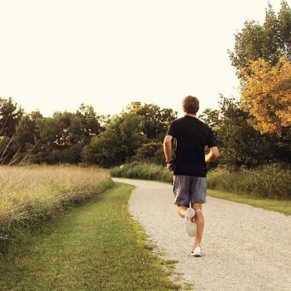 Un homme de dos court sur un chemin dans la campagne.