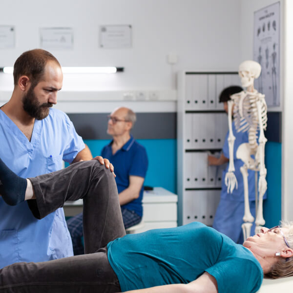 Un chiropracteur manipule le genou d'une patiente.