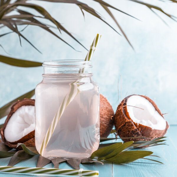 De l'eau de coco avec des noix de coco en arrière-plan.