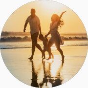 Un couple et leur enfant marchent sur la plage au coucher de soleil.