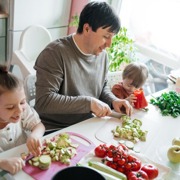 Un père de famille cuisine avec ses deux enfants.