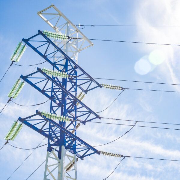 Un pylone électrique sous un ciel bleu nuageux.