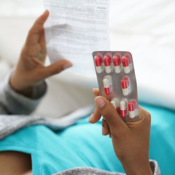 Une dame tient des médicaments et une notice d'utilisation dans l'autre main.