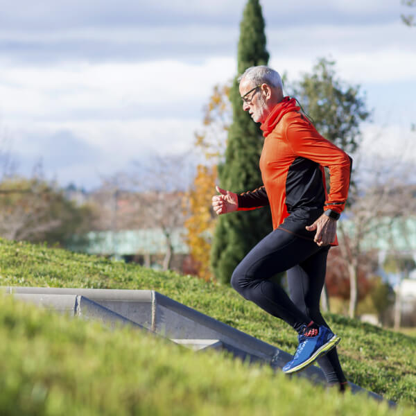 Un homme senior court sur une colline.
