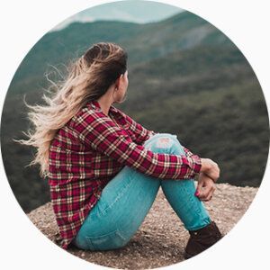 Une femme assise au sol regarde l'horizon au loin.