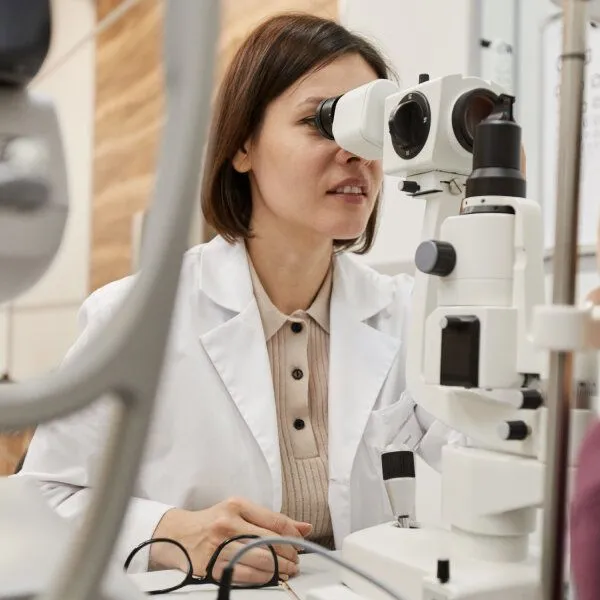 Un docteur ophtalmologiste regarde dans un instrument pour mesurer une DMLA.