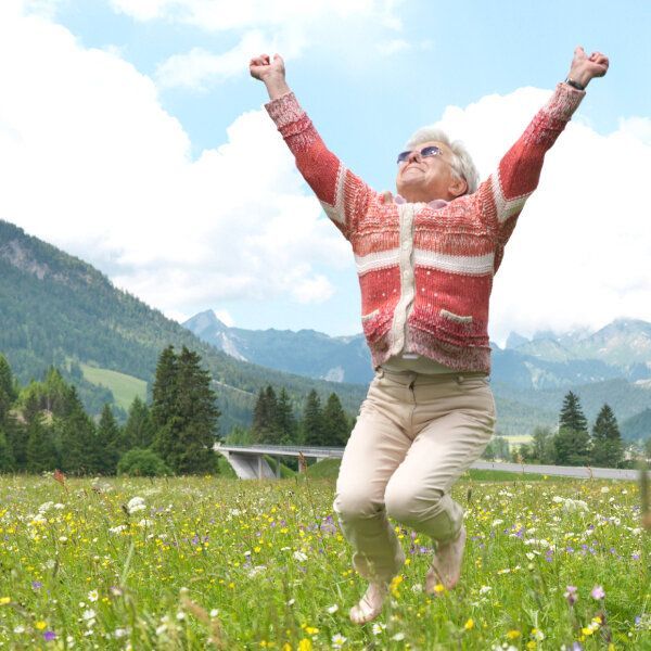 Une dame âgée pleine d'énergie, joyeuse, dans un cadre naturel campagnard.