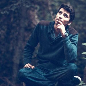 Un jeune homme assis semble pensif.