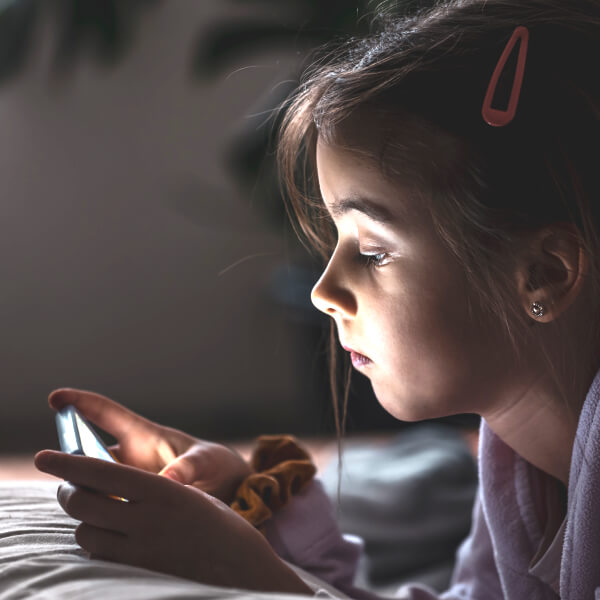 Une fille de nuit utilise son smartphone, inconsciente des dangers des ondes électromagnétiques.