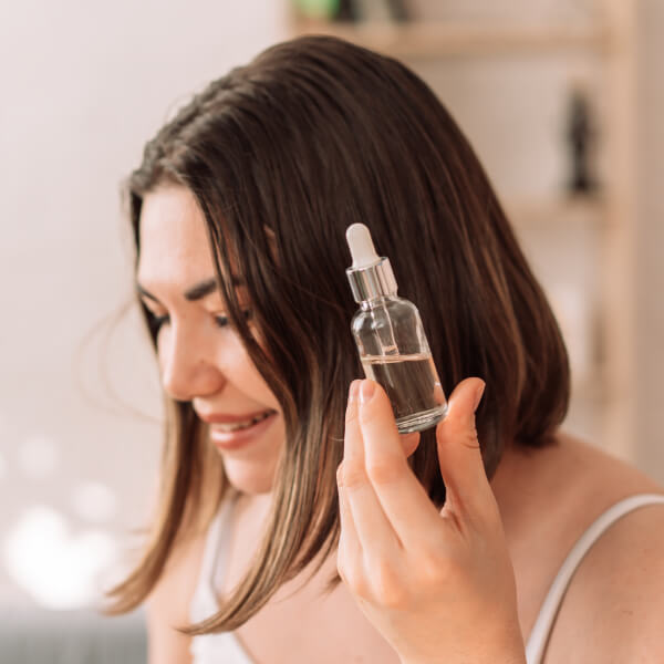 Une jeune femme tient dans sa main une pipette d'extrait de pépins de pamplemousse.