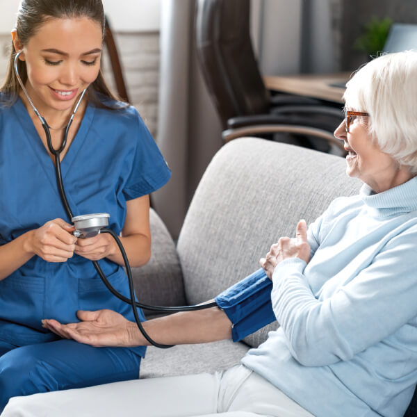 Une infirmière mesure la pression sanguine d'une patiente âgée.