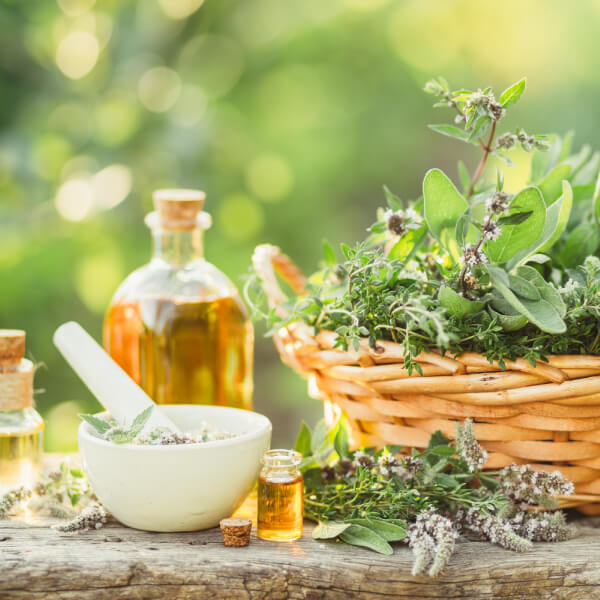 Mortier, bouteille d'huile et plantes médicinales séchées.
