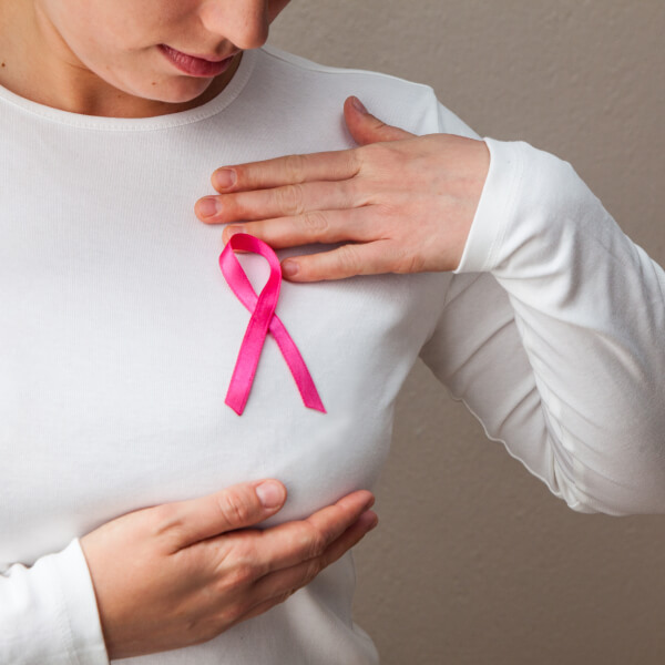 Une femme affiche sur son haut blanc le symbole de solidarité contre le cancer du sein.