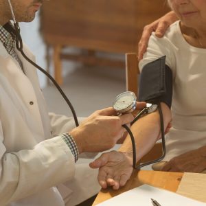 Un docteur mesure la tension artérielle d'une patiente âgée.