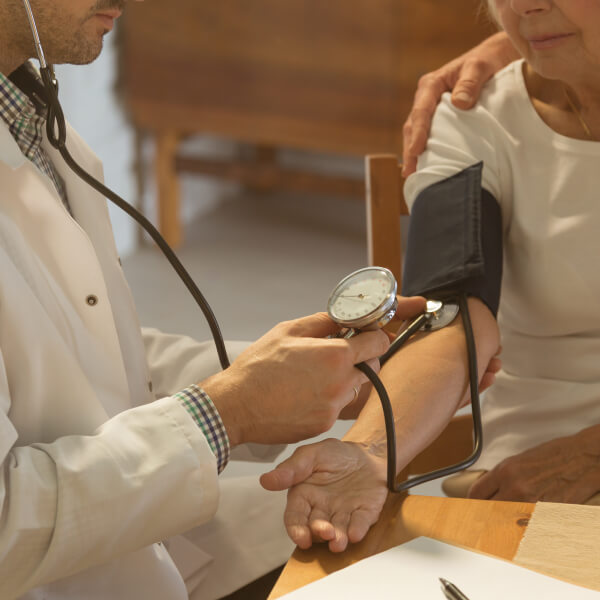 Un docteur mesure la tension artérielle d'une patiente âgée.