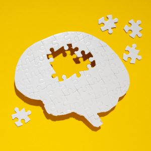 Un puzzle sous forme de cerveau humain sur fond jaune.