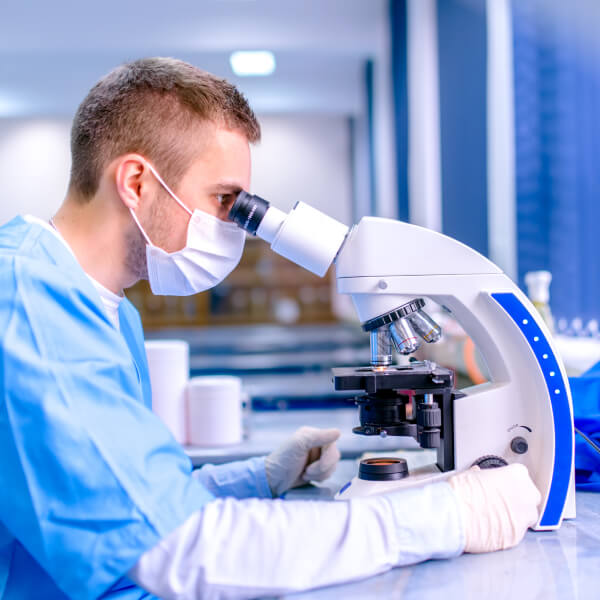 Un scientifique en laboratoire observe dans un microscope.