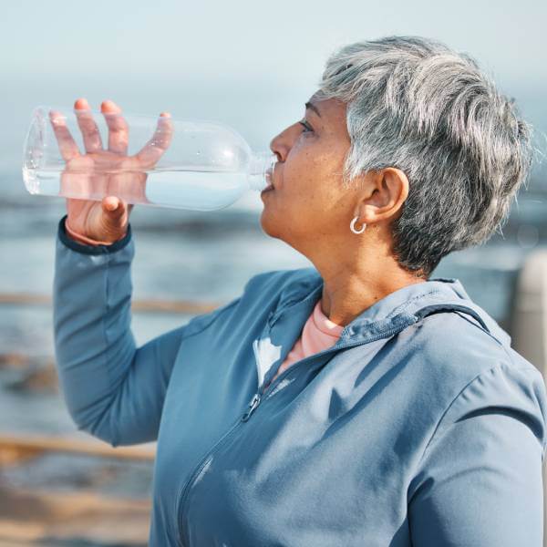 Une dame mature boit de l'eau.