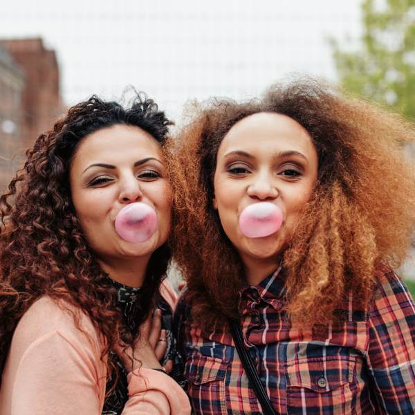 Deux amies mâchent du chewing-gum sans sucre pour renforcer les dents.
