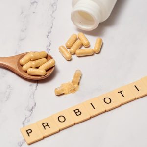 Une cuillière en bois avec des gélules de probiotiques.