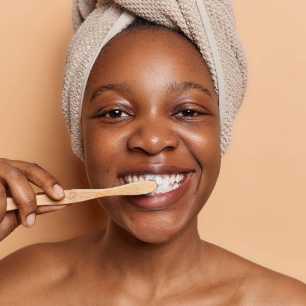 Une femme se brosse les dents pour assurer une reminéralisation dentaire.