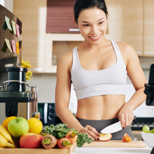 Une jeune femme athlétique cuisine fruits et légumes.