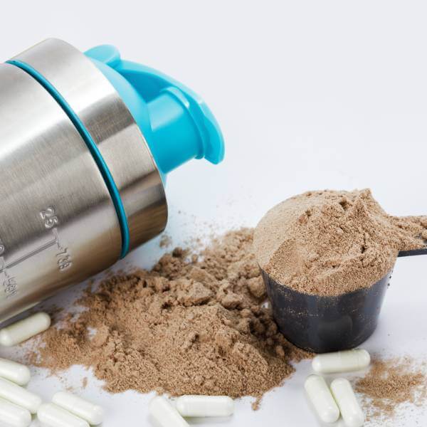 Un shaker de protéines à coté d'un scoop de L-Glutamine.