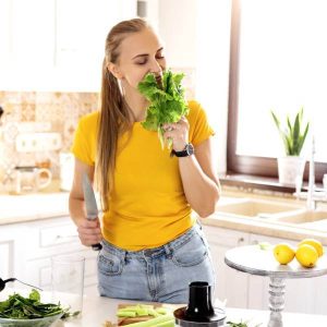 Une femme à la cuisine sent un bouquet de plantes pour maigrir.