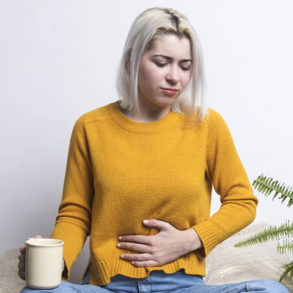 Une femme se tient le ventre balloné manquant d'enzymes digestives.