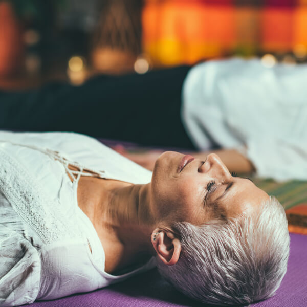 Une dame âgée allongée sur un tapis de yoga, détendue.