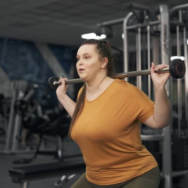 Une femme en surpoids fait de l'exercice en salle de gym.