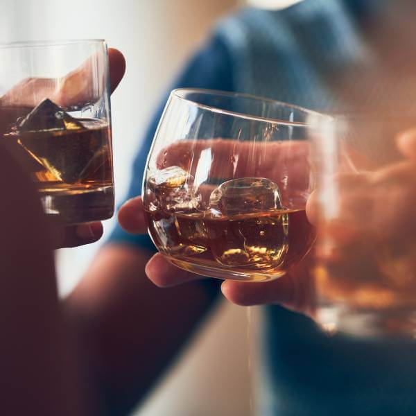Gros plan sur deux personnes qui trinquent avec de l'alcool.