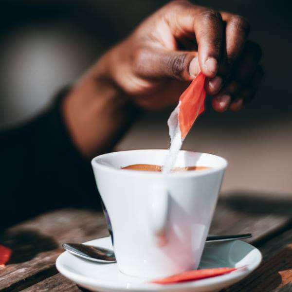 Quelqu'un ajoute du sucre raffiné dans un café.