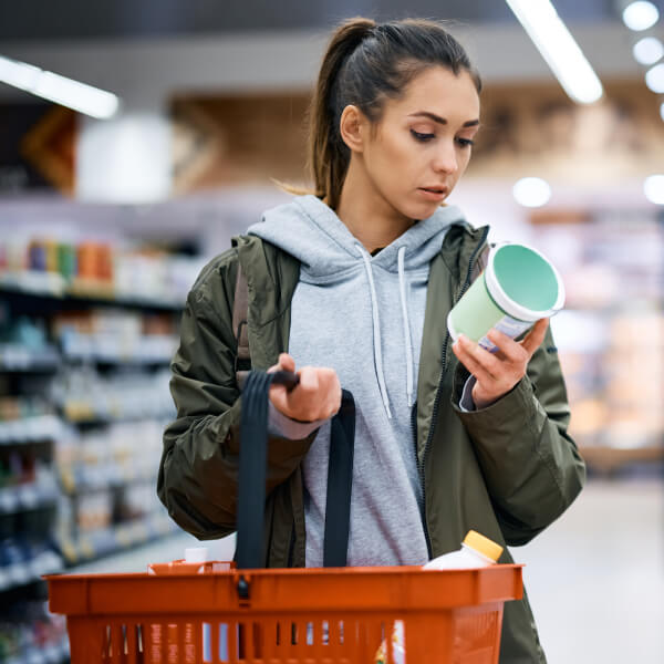 Une jeune femme dans un supermarché étudie l'étiquette d'un yaourt pour les intestins.