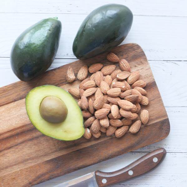 Des avocats et des amandes sur une planche de cuisine.