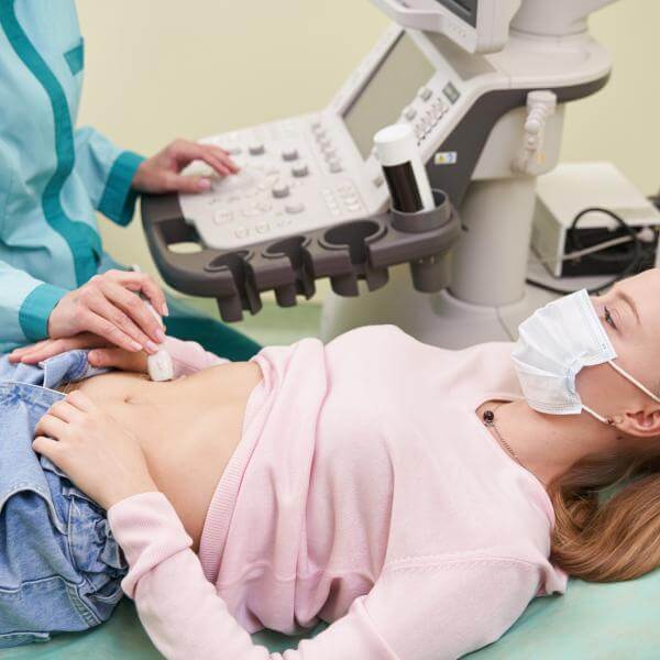 Un gastro-entérologue examine l'estomac d'une patiente avec un appareil à ultrason.