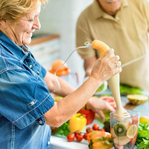 Un couple de seniors cuisinent des légumes et des fruits.