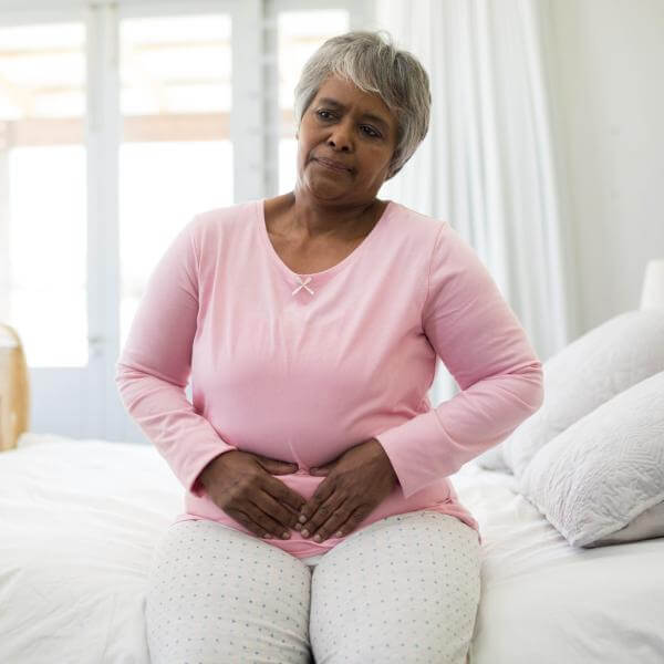 Une dame se tient le ventre se sentant lourde après avoir mangé.