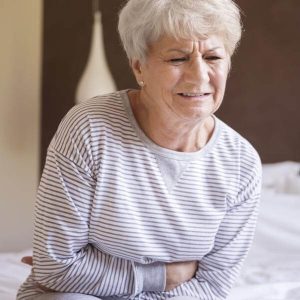 Une dame se tient le ventre de douleur se demandant si son estomac est malade.