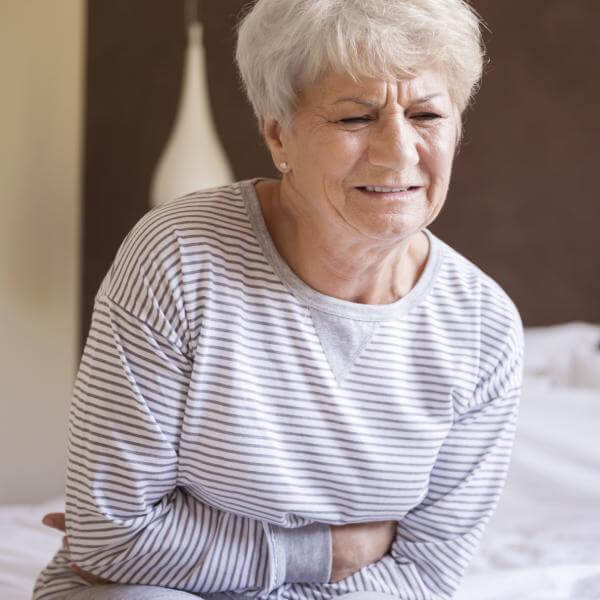 Une dame se tient le ventre de douleur se demandant si son estomac est malade.