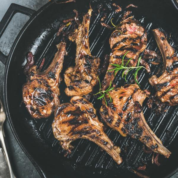 Des cotelettes d'agneau grasses en train d'être grillées.