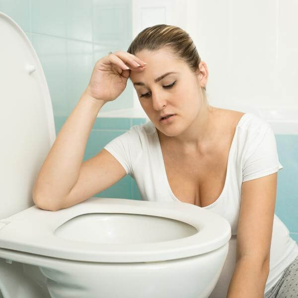 Une femme au-dessus d'un bol de toilette après avoir vomi.